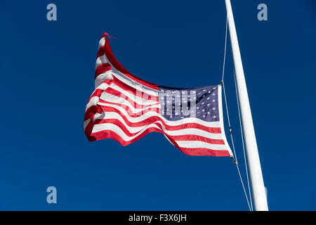 A bright red white and blue American flag flapping in the wind against the sky. Stock Photo