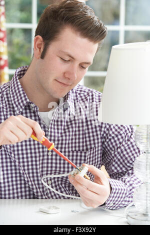 Man Wiring Electrical Plug On Lamp At Home Stock Photo