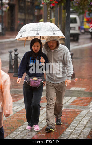Couple holding an umbrella walking in the rain, Vancouver. Stock Photo