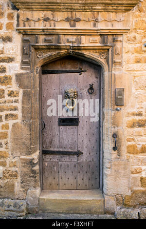 Old oak paneled front door with lion door knocker. Stanton, cotswolds, Gloucestershire, England Stock Photo