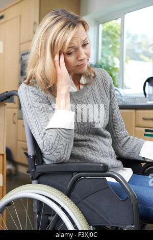 Depressed Woman Sitting In Wheelchair At Home Stock Photo