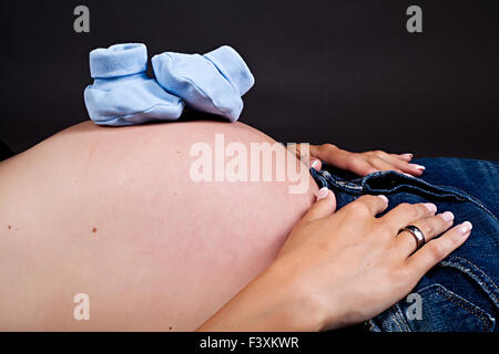 Babyshoes on pregnant belly Stock Photo