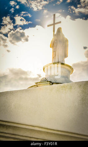 Angel with cross towers over the legendary crypts in the oldest and most famous St. Louis Number One cemetery in New Orleans, LA Stock Photo