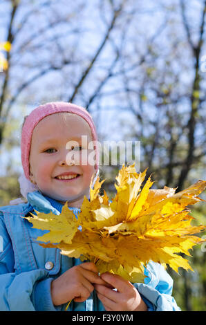 Smiling little girl holding fall leaves Stock Photo