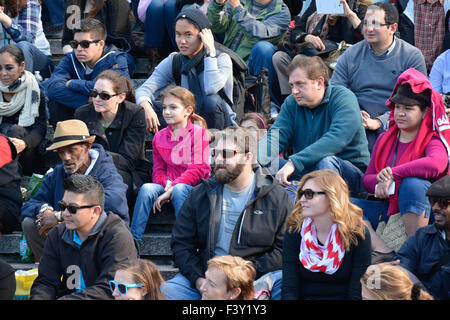 Multitude of diverse people in the USA sitting on bleachers reacting and watching an event Stock Photo