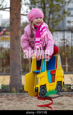 Little girl on the carousel in the autumn Stock Photo