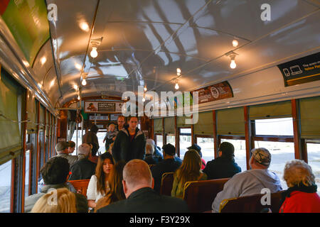 Passengers sit on vintage mahogany benches inside a Streetcar traveling and taking on fares in New Orleans, LA Stock Photo