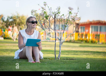 Beautiful woman sitting barefoot on a lawn Stock Photo