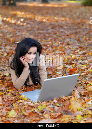 Pretty Smiling Woman Lying on Ground with Laptop Stock Photo