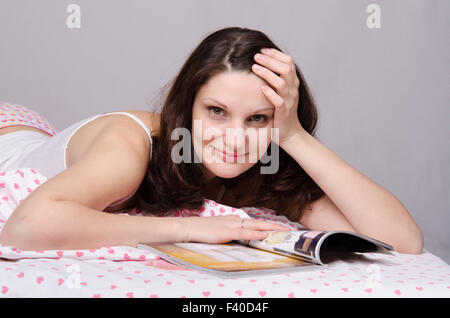 Beautiful girl with a magazine in bed Stock Photo