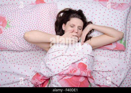 The girl woke up yawning in bed Stock Photo