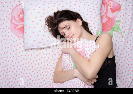 Woman hugging pillow in bed Stock Photo