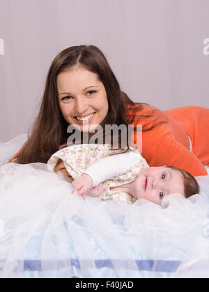 Mom and baby lying on the bed having fun Stock Photo