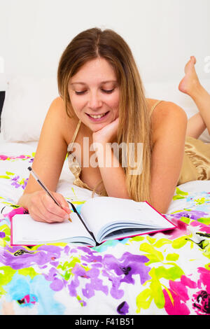 young woman ion her bed writing in her diary Stock Photo