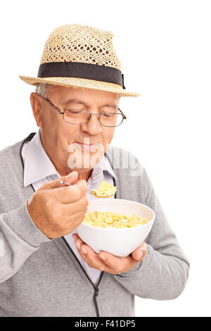 Close-up on a senior gentleman eating cereal with a metal spoon isolated on white background Stock Photo