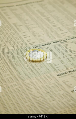 News paper Stock market financial page showing stocks and shares with a British two pound coin Stock Photo
