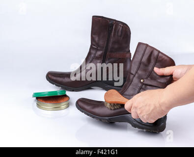 woman's hand polishing boot with shoe brush on white background Stock Photo