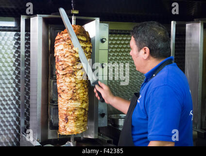 Döner kebab meat on vertical rotisserie Stock Photo