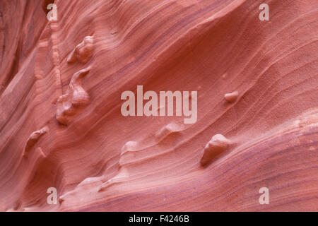 Eroded sandstone canyon walls showing ancient sand layers and standout features in abstract patterns. Stock Photo