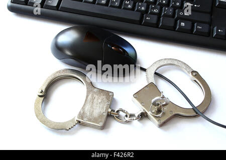 computer hacker equipment and hand cuffs locked up on white table Stock Photo