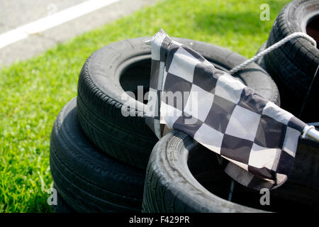 Checkered flag resting over the tyres of the track, Shallow depth of field Stock Photo