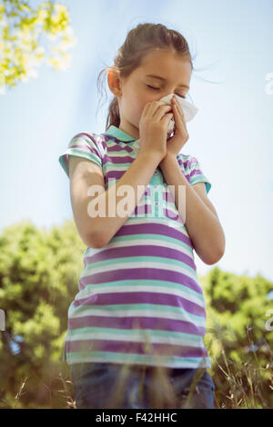 Cute little girl blowing her nose in park Stock Photo