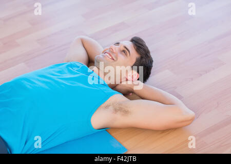 Smiling man lying on exercise mat Stock Photo