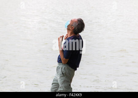 Vietnamese mature man practicing tai chi on the shore of hoan kiem lake in Hanoi, face mask against pollution,Vietnam Stock Photo