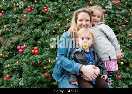 Mother and children posing in front of outdoor Christmas tree, portrait Stock Photo