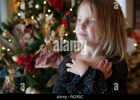 Girl daydreaming with Christmas tree in background