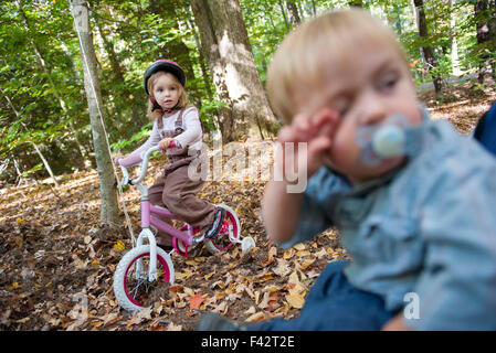 Little girl riding bike in wooded area Stock Photo