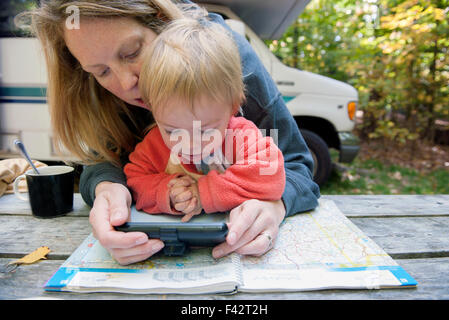 Mother holding child on lap while using atlas and GPS to plan road trip Stock Photo