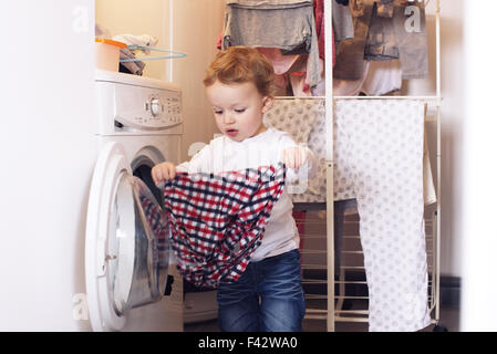 Little boy taking clothes out of dryer Stock Photo