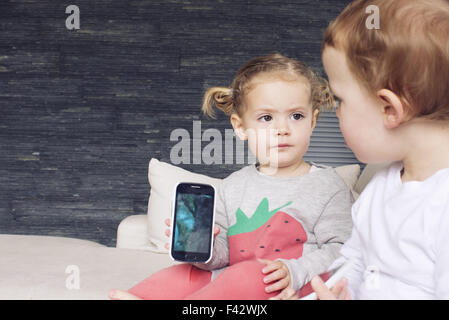 Little girl showing smartphone to her brother Stock Photo