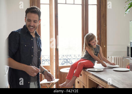 Girl helping father set table for family meal Stock Photo