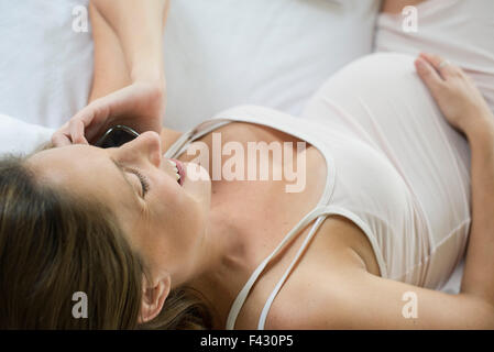 Pregnant woman using cell phone to stay in touch with friends and family Stock Photo