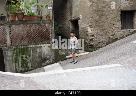 A young boy standing on a sloping pavement in an Italian village. Stock Photo