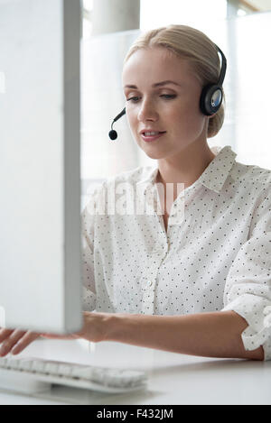 Woman using desktop computer and headset in office Stock Photo