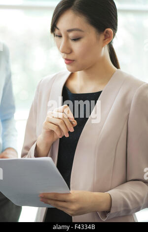 Businesswoman reviewing document with colleague Stock Photo
