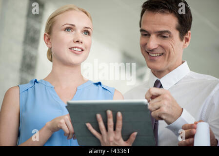 Business professionals looking at digital tablet together and laughing Stock Photo