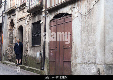 An elderly lady standing in the doorway looking down a street. Stock Photo