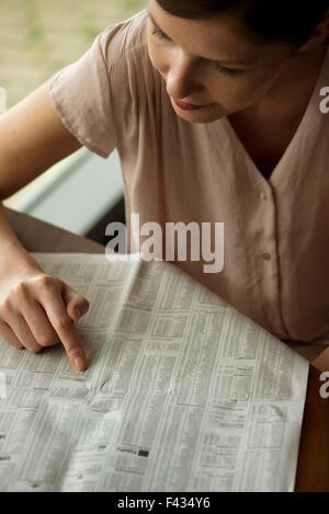 Woman shopping for real estate in newspaper classified ads Stock Photo