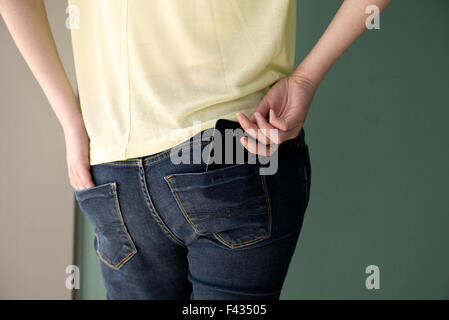 Woman placing cell phone in back pocket Stock Photo