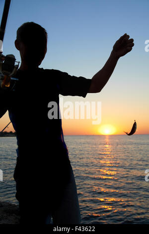 Fisherman fishes at the sunset Stock Photo - Alamy
