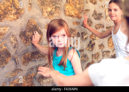 Girls leaning against wall during game of tag Stock Photo