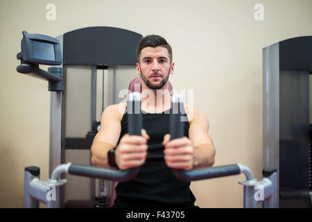 Focused man working out on the weights machine Stock Photo