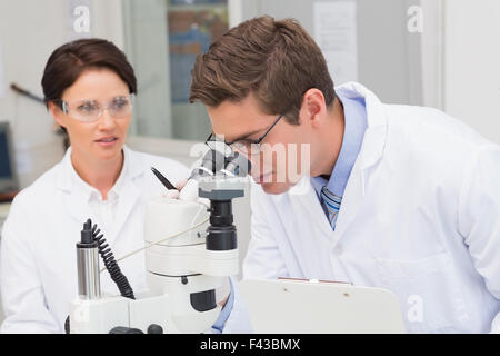 Scientists looking attentively in microscope Stock Photo