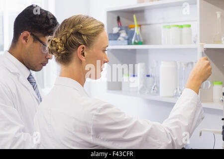 Concentrated scientists looking at beaker Stock Photo