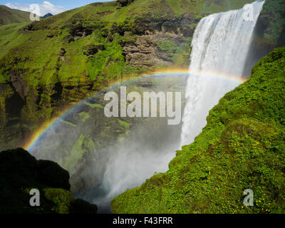 Skogafoss waterfall, a cascade over a sheer cliff, and a rainbow in the mist. Stock Photo