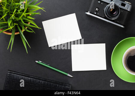 Office leather desk table with blank photo frames, camera, supplies, coffee cup and flower. Top view with copy space Stock Photo
